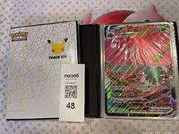 Front cover of the first Pokémon 25th Anniversary jumbo card binder with Pikachu emblem, showing white cover with Pokemon silhouettes and multiple jumbo cards in protective sleeves.