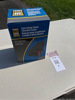 Boxed two-stage snow thrower cover branded PowerFist on a table outdoors with MaxSold tag visible.