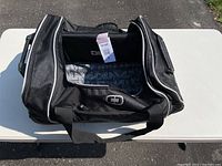Open view of the black Ogio duffle bag showing the main compartment with patterned lining and tag attached inside.