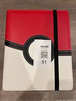 Front side of binder showing the red and white Pokeball design with black circle and elastic strap.