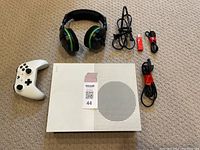 All items included in the bundle displayed on carpet: Xbox console, controller, headset, cables, and USB adapter.
