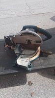 Side view of the Mastercraft compound mitre saw showing the blade, base with angle markings, and handle.