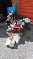 Full view of assorted Christmas decorations including plush dolls, gift bags, artificial tree and storage bin