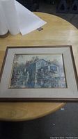 Framed print of a mill on a round wooden table.