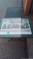 Overview photo of the framed limited edition Toronto Maple Leafs print on an outdoor plastic table. The print is black-and-white showing players as hospital staff. Frame glass is cracked.