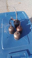 Photo of four vintage metal oil cans placed on blue plastic surface, showing a large oil can with flexible metal hose and three smaller oil cans with narrow fixed spouts.
