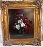 Full view of floral oil painting in large ornate gold frame showing flowers and raised detailed border.