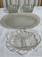 Photo showing all four dishes: one large frosted glass oval dish, two small clear crystal dishes, and one clear divided appetizer dish.