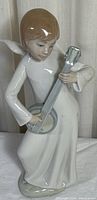 Full front view of porcelain angel figurine playing guitar showing robes, guitar and face