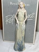 Front view of the Royal Doulton porcelain figurine in front of its branded box.