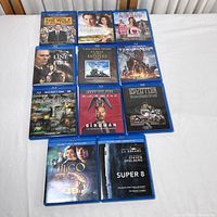 Full view of 12 Blu-Ray movie discs in cases laid flat on white surface.