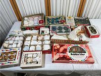 Overview photo showing multiple vintage Christmas ornament boxes and vintage Bubble Lites string lights on table