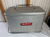 Front view of aluminum cooler with handle and textured pattern.