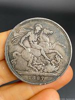 Front view of 1887 British silver Sovereign/Crown coin showing St. George slaying the dragon with the date at the bottom.