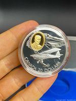 Obverse of coin showing airplane and gold-colored inset portrait.