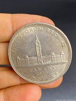 Obverse side of 1939 Canadian silver dollar showing Parliament building and inscriptions.
