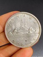 Obverse side of the 1965 Canadian silver dollar showing the Voyageur design with two men in a canoe and the year 1965.