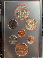 Front side of six different sized coins with detailed reverse designs including landscapes and symbols of Canada, all set inside a plastic display case.