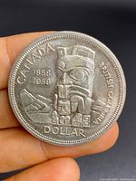 Front side of the coin showing the Totem Pole design, "CANADA," years "1858 1958," and "BRITISH COLUMBIA" text with "DOLLAR" at the bottom.
