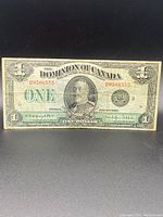 Front side of Dominion of Canada one dollar bill showing portrait of King George V and serial number D9508555 in worn condition.