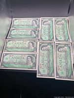 Front side of 8 Canadian $1 bills displaying Queen Elizabeth II portrait and denomination.