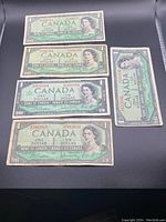 Front sides of five Canadian one dollar bills showing serial numbers and portrait of Queen Elizabeth II