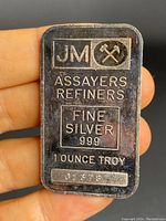 Front side of Johnson Matthey silver bar showing JM logo, crossed hammers, assayers refiners, fine silver .999, 1 ounce troy and serial number 01378.
