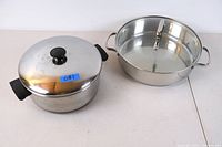 Two cooking pots, one with lid and black handles, one stainless steel with divider