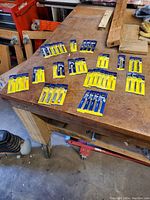 Photo showing 41 new Irwin Hanson hand taps spread on a workbench surface.
