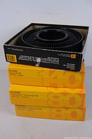 Four Kodak slide trays in original boxes with one open box showing black plastic tray.