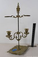 Full front view of the brass double candle holder with a ruler for scale.