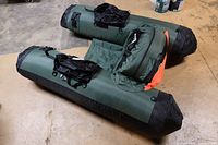 Full view of two green and black inflatable float tubes laid on a floor, showing overall size and shape