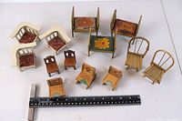 Top view of 13 small wooden doll house furniture pieces including chairs and benches with floral patterns and fabric cushions alongside a ruler for scale.