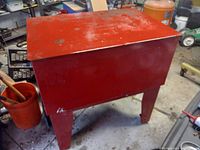 Red metal floor standing parts washing cabinet with hinged lid, showing wear and rust, photographed from above and side angles.