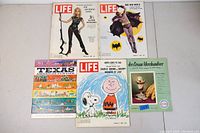 Full view of five vintage magazines and ephemera laid flat on a light surface