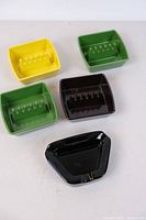 Five vintage ceramic ashtrays placed on a white surface, varied shapes and colors visible