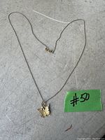 Full view of 10K gold chain with butterfly pendant laid flat on a surface with a green tag numbered 50.