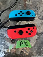 Photo shows two Nintendo Switch Joy-Con controllers, left in neon blue and right in neon red, placed on a glass surface.