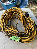 Coiled yellow and black 50-foot extension cord with male and female ends shown on an outdoor table.