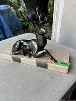 Side angle of reclining bronze elk on marble base
