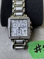 Close-up view of the Bulova watch showing square face, chronograph dials, date, and metal bracelet.