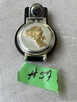 Phillip Wells clip-on belt watch with silver-tone round cover embossed with a gold-tone train design, attached to black synthetic leather strap with snap button.