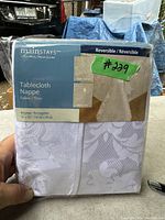 Packaged Mainstays reversible rectangle tablecloth with visible product label and dimensions.