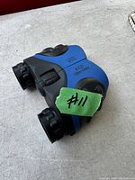 Angle view of a pair of small binoculars, showing the magnification and field of view text on the top side and focusing wheel.