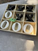 Top-down view of the 3x3 wooden tic tac toe grid filled with black X and white O pieces.