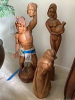 Three carved wooden sculptures displayed together showing different angles and details