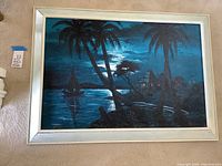 Full view of the large framed painting depicting the tropical night scene with water, palm trees, and a boat under a dark sky.