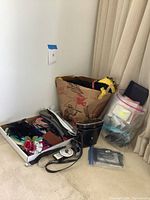 Binoculars in black leather case, cardboard box with mixed small bags and fabric items, clear plastic bag with more fabric pieces and accessories