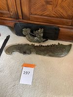 Full view of heavy Chinese stone sword with dragon carvings next to matching dragon sculpture stand