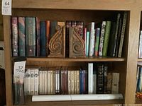 Bookshelf with two shelves containing books including boxed Harry Potter set and multiple titles along with two wooden carved bookends.